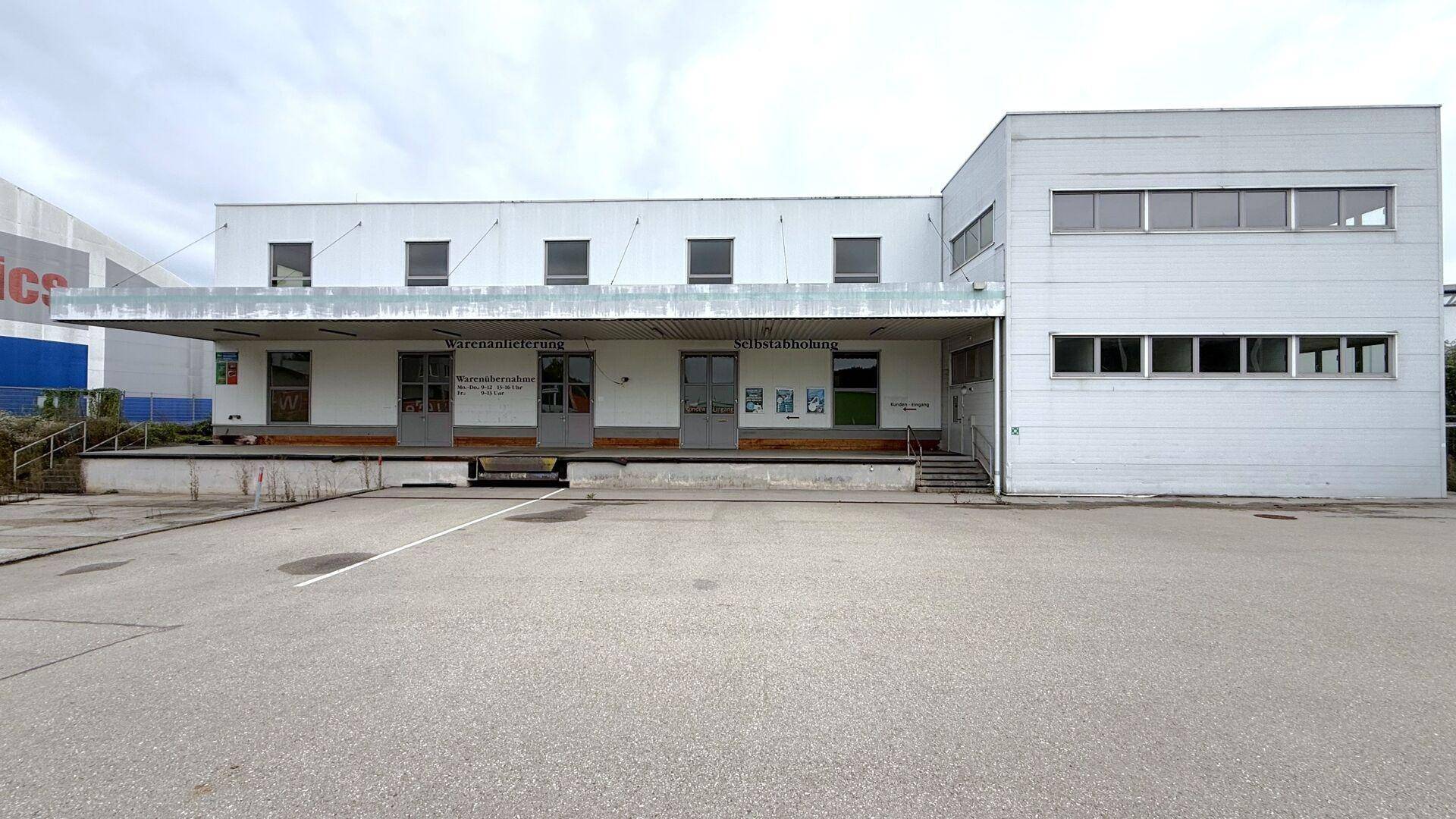 Vorderansicht des Gewerbegebäudes mit Laderampe und mehreren Türen für Warenanlieferung.
