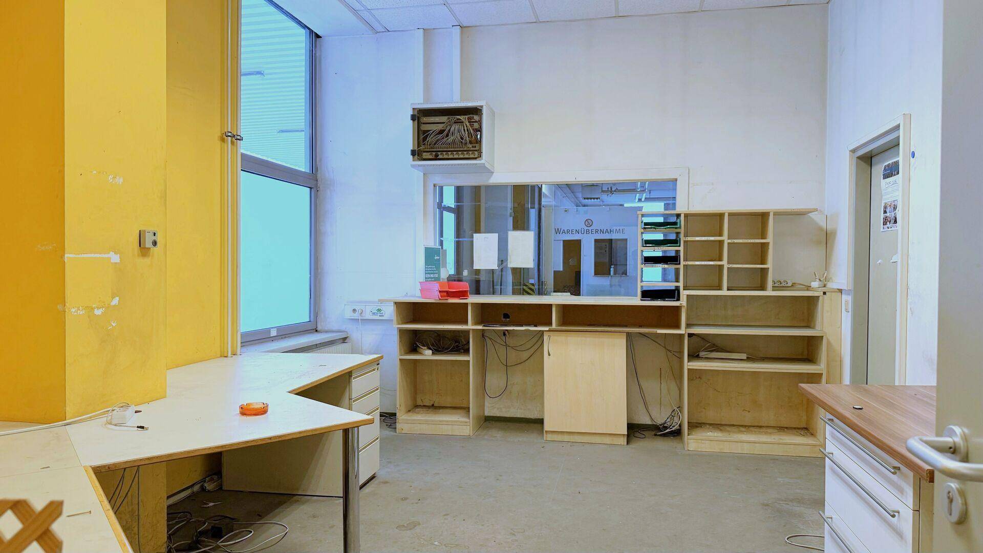 Büro- oder Empfangsbereich mit eingebauten Regalen, Schreibtischen und einem Fenster.
