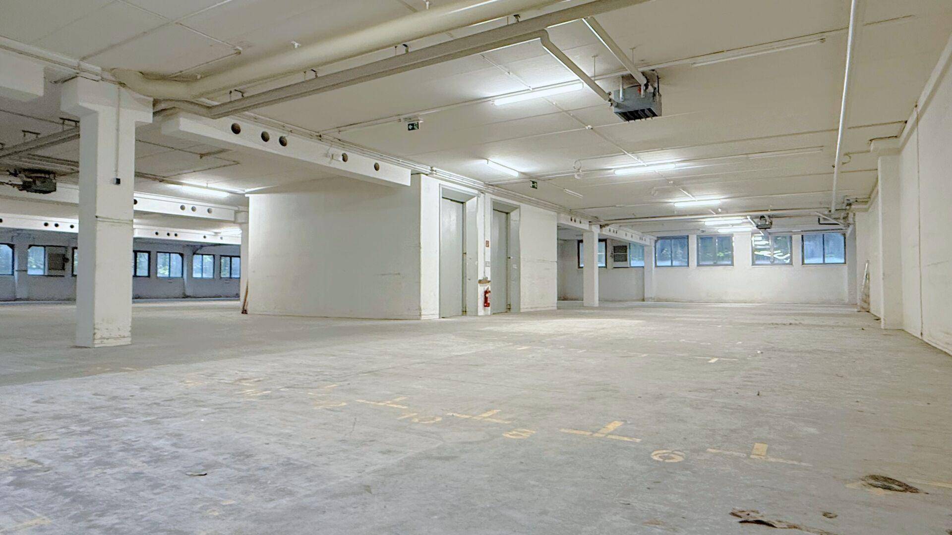 Weitläufiger Lagerraum mit Betonboden, Säulen und einer markanten runden Wandstruktur.