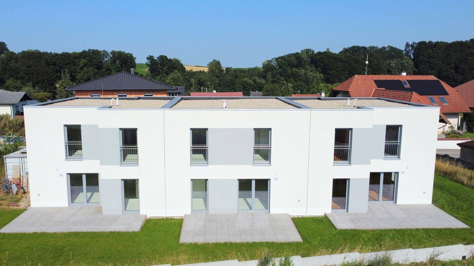 Ansicht der modernen Reihenhausfassade mit großen Fenstern und kleinen Balkonen.