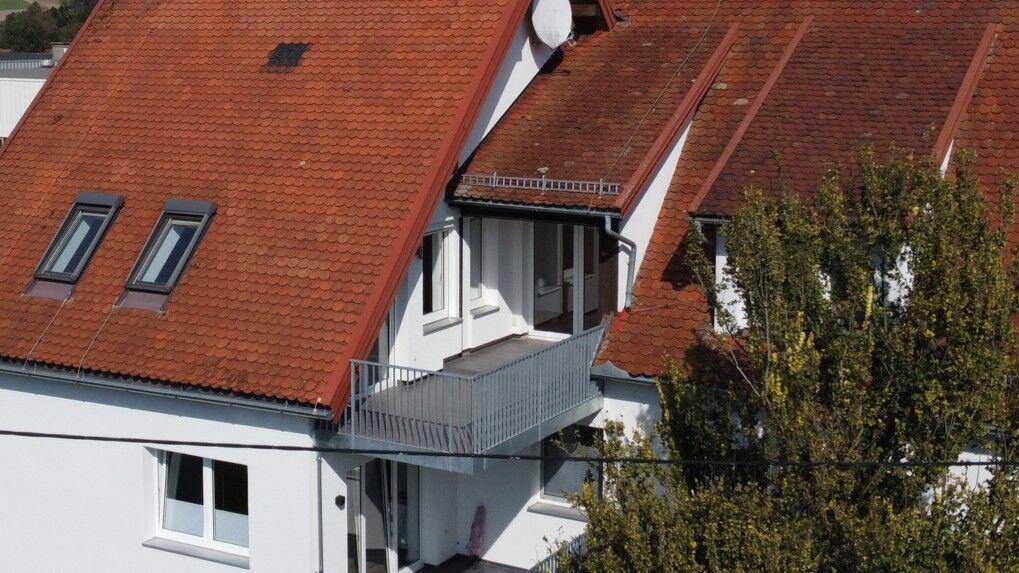 Nahaufnahme des Gebäudes mit rotem Ziegeldach, Dachfenstern und einem Balkon.