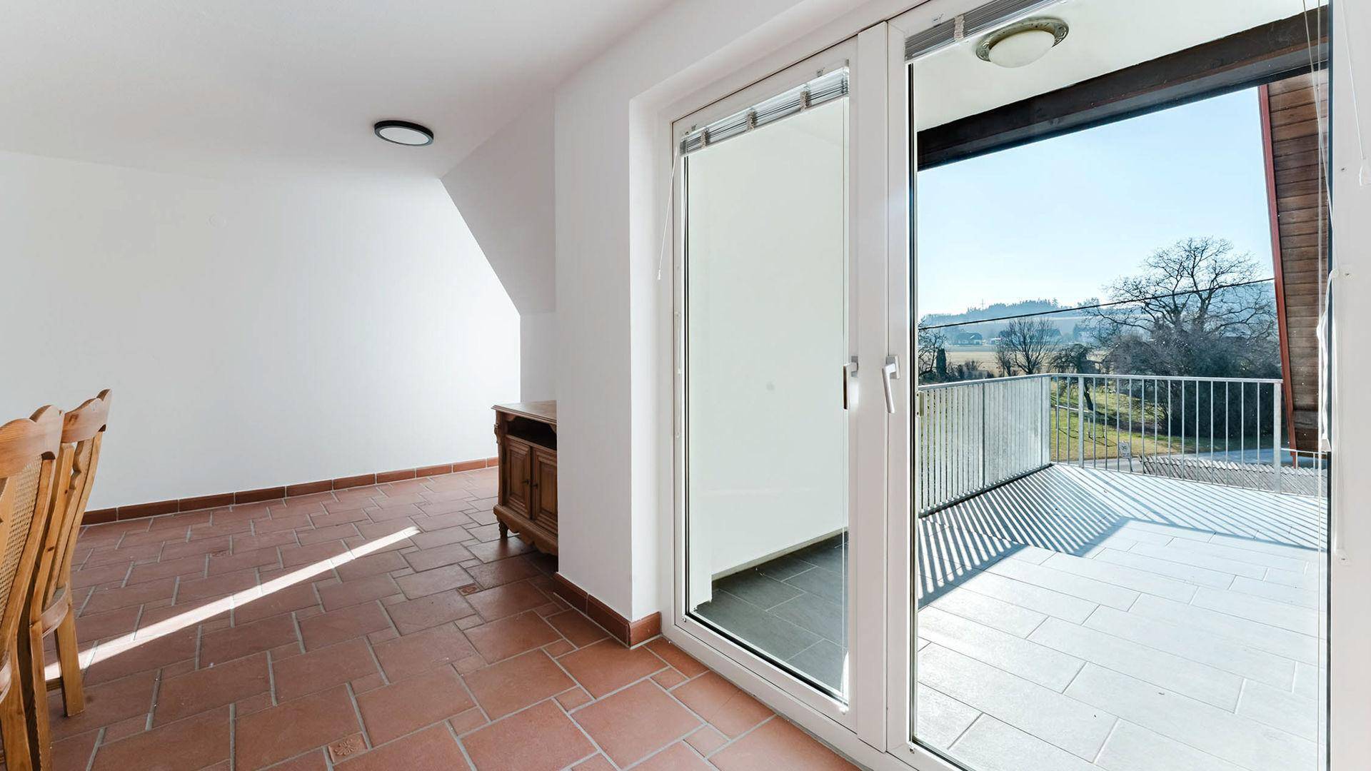 Gemütlicher Essbereich mit Terrakotta-Fliesenboden und großem Schiebetürzugang zu einem sonnigen Balkon.