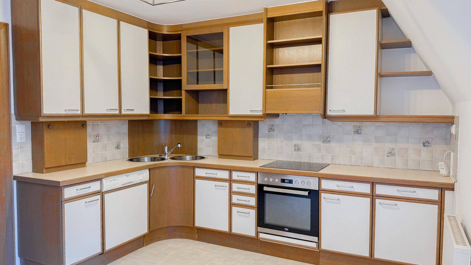Einbauküche mit Holzschränken, weißen Fronten, Induktionskochfeld und integriertem Backofen.