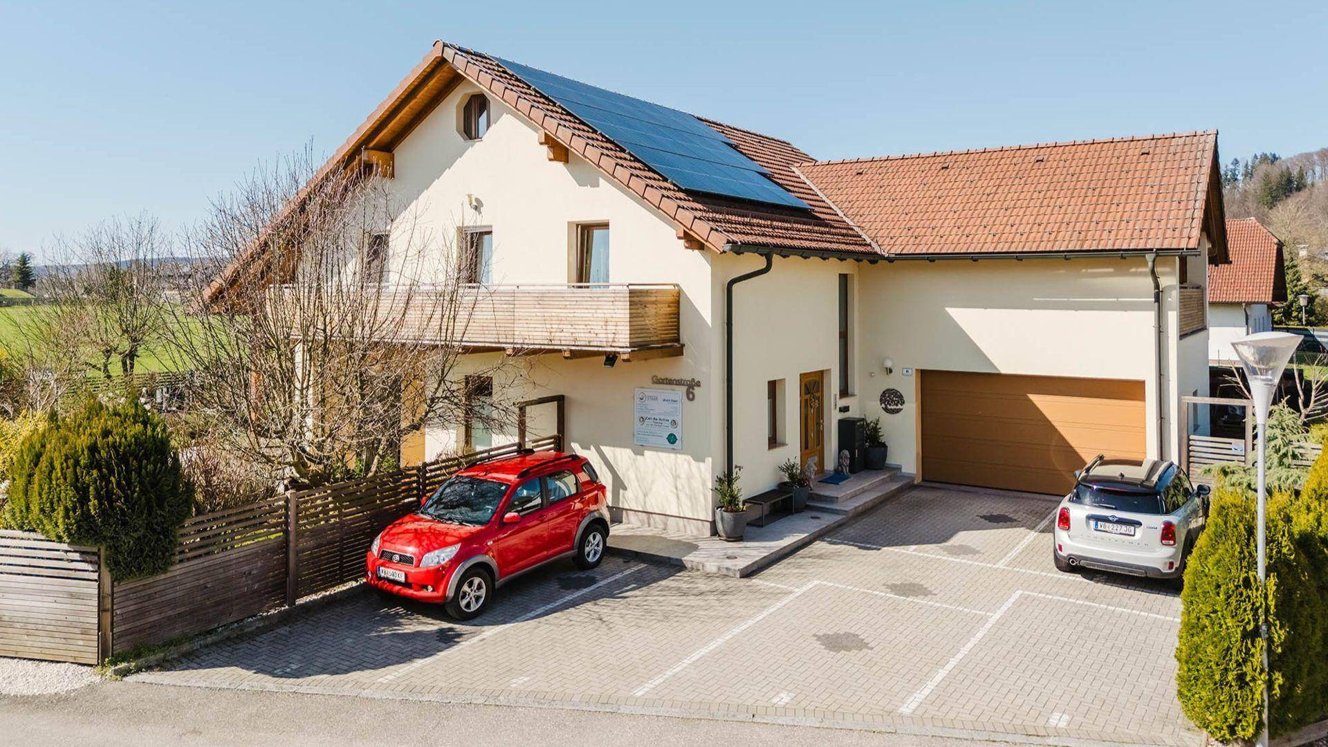 Ansicht eines Hauses mit Satteldach, Solaranlage, Parkplätzen und integrierter Garage.