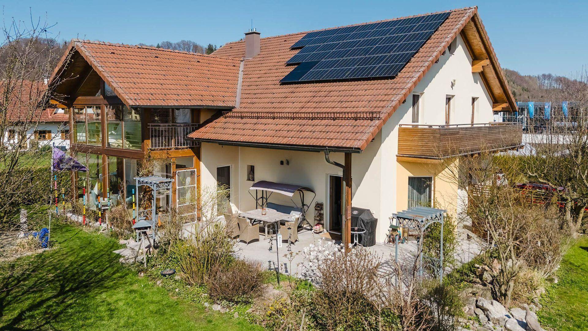 Rückansicht des Hauses mit Terrasse, Garten und Solaranlage auf dem Dach.