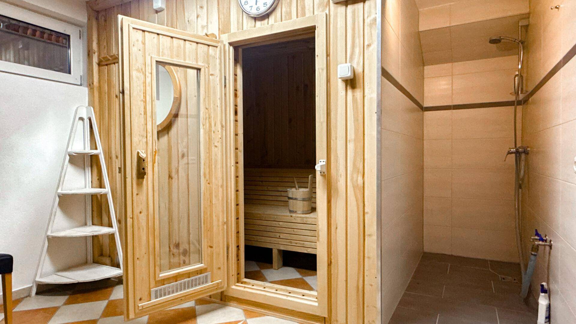 Holzsaunakabine in einem Wellnessbereich, ergänzt durch eine praktische Duschgelegenheit.