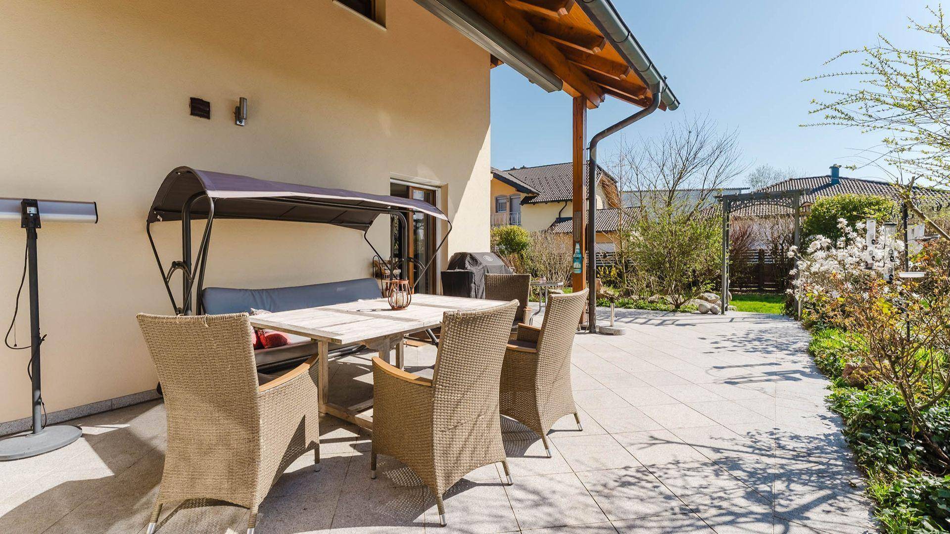 Geräumige gepflasterte Terrasse mit Sitzgelegenheiten und Blick in den Garten.