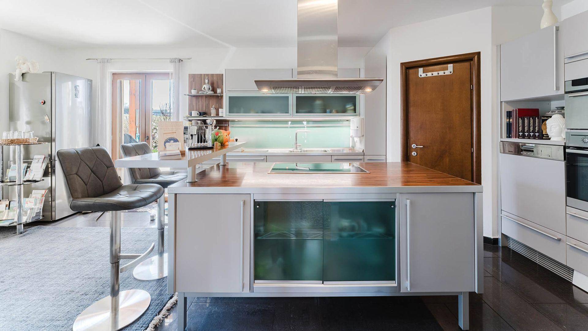 Moderne Küche mit Kücheninsel, integrierten Geräten und dunklem Fliesenboden.