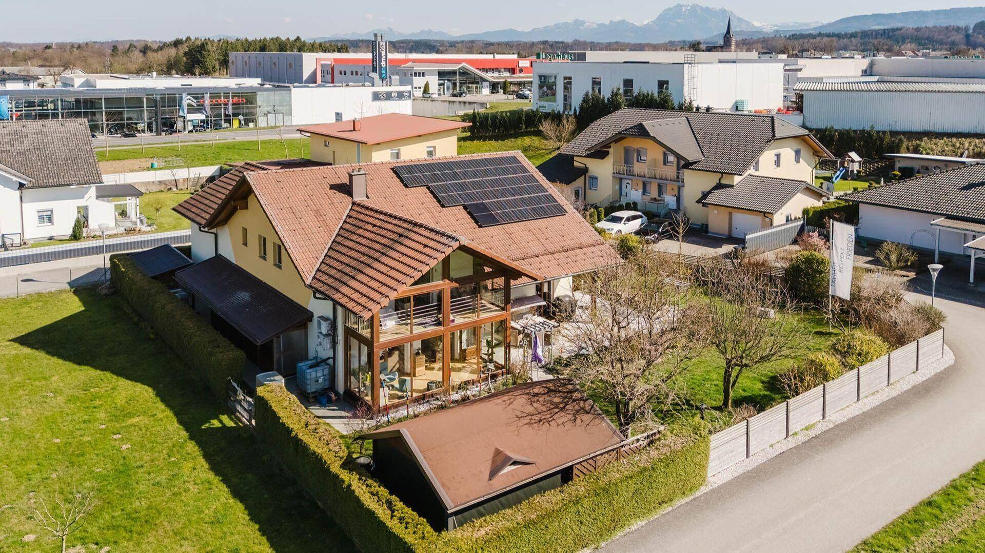 Luftaufnahme des Anwesens mit Haus, Garten und umliegender Nachbarschaft mit Bergblick.