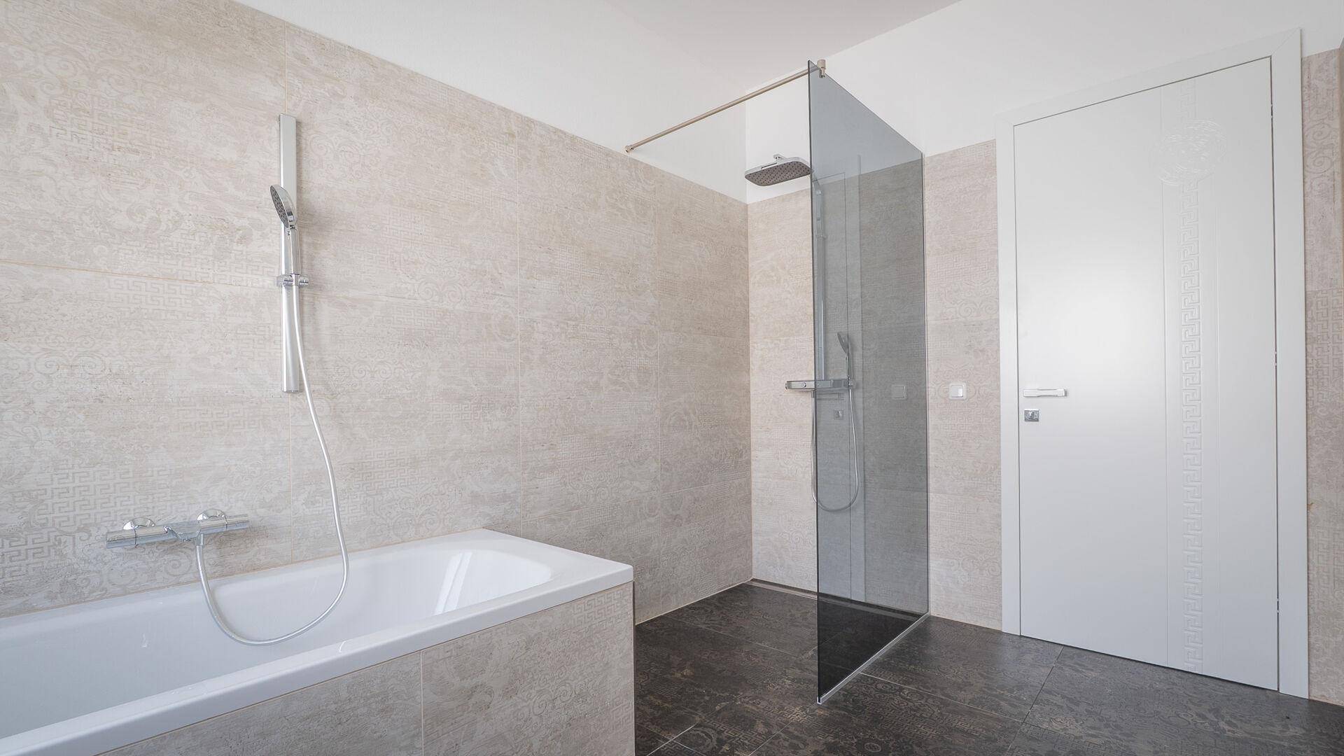 Modernes Badezimmer mit Badewanne, begehbarer Dusche und hellen, gemusterten Wandfliesen.