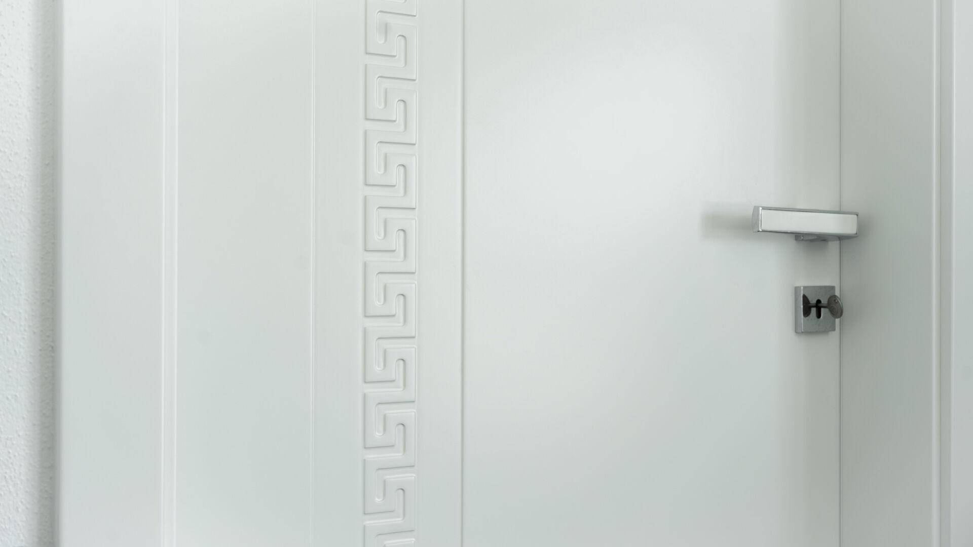 Detailansicht einer weißen Tür mit elegantem, eingeprägtem Muster und moderner Klinke.