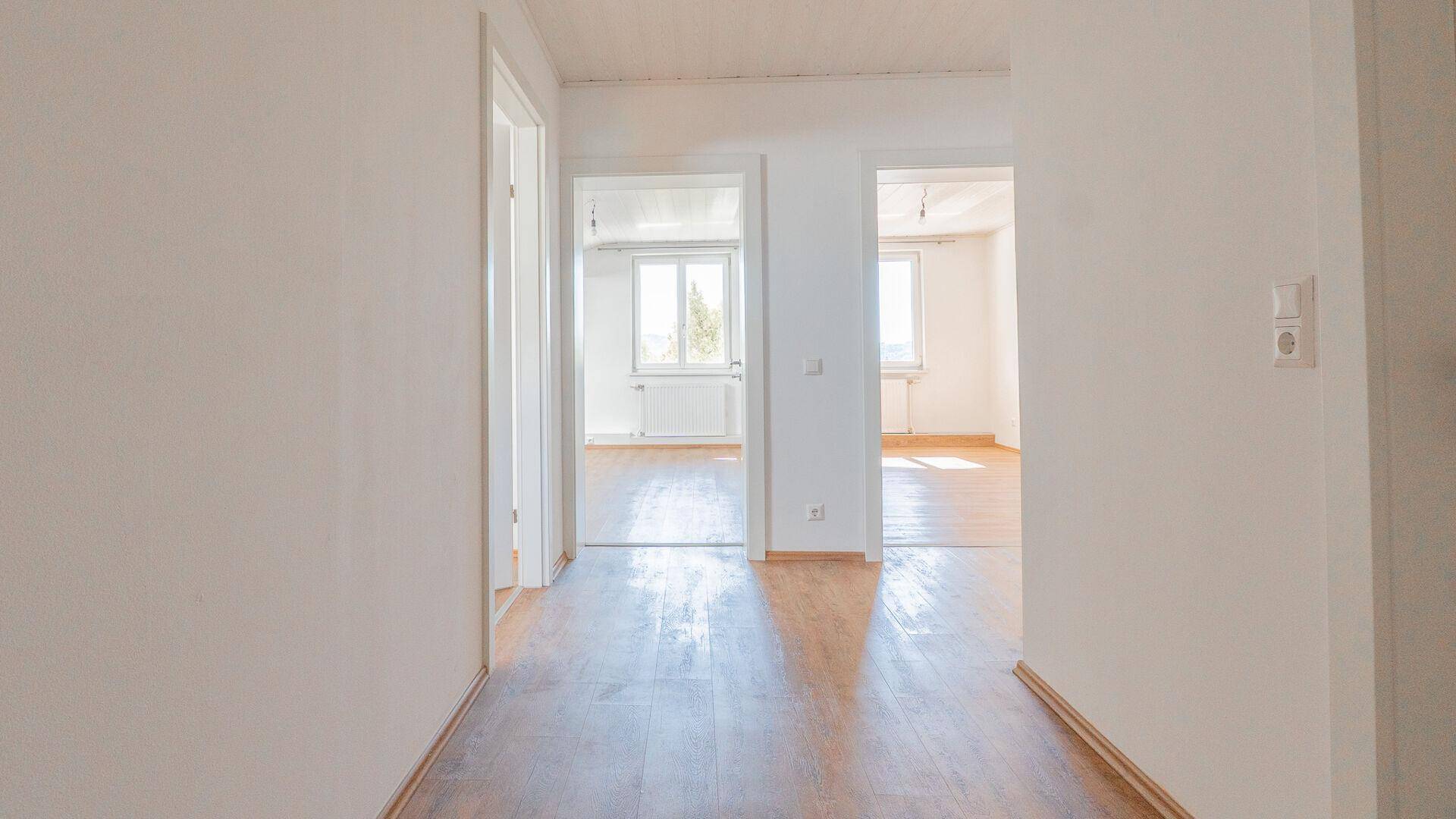 Heller Flur mit Laminatboden, der den Zugang zu mehreren Zimmern der Wohnung ermöglicht.