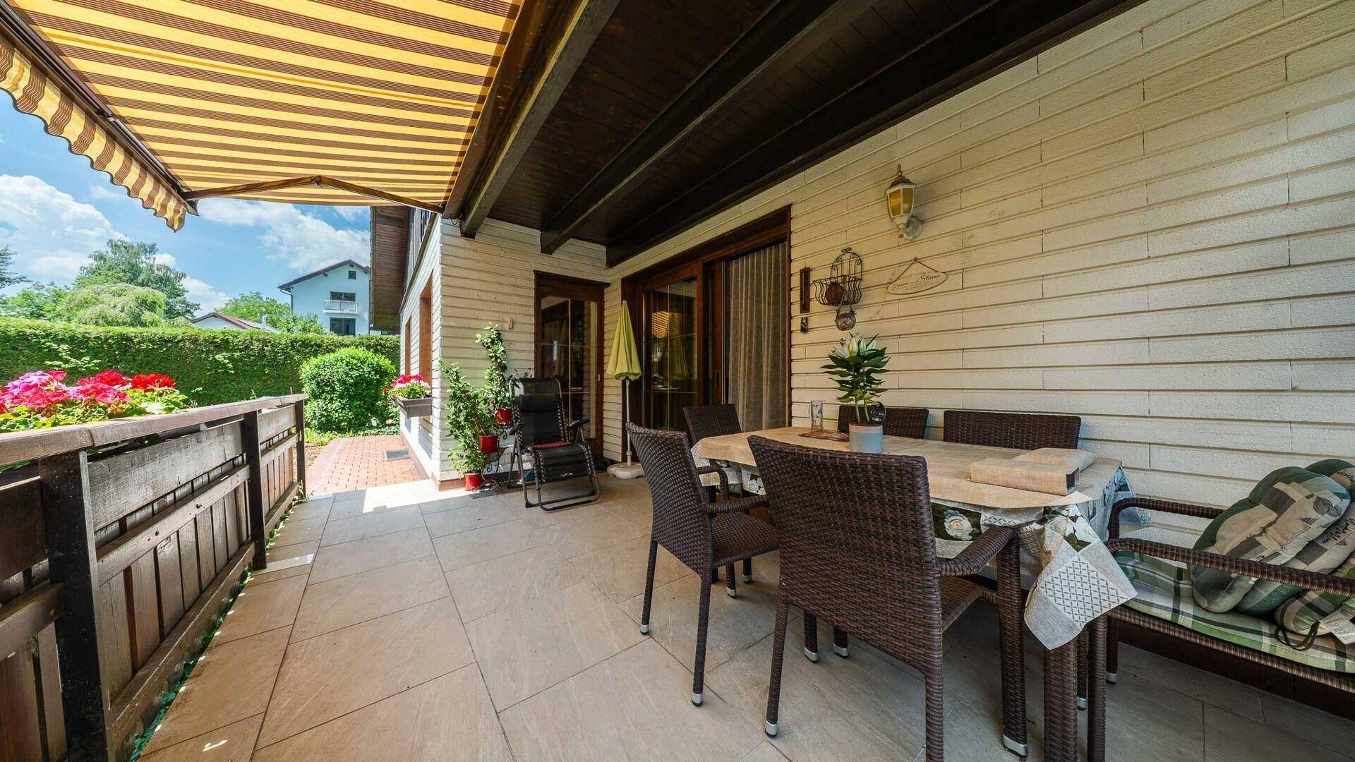 Sonnige Terrasse mit Essbereich und bequemen Stühlen, ideal für Mahlzeiten im Freien.