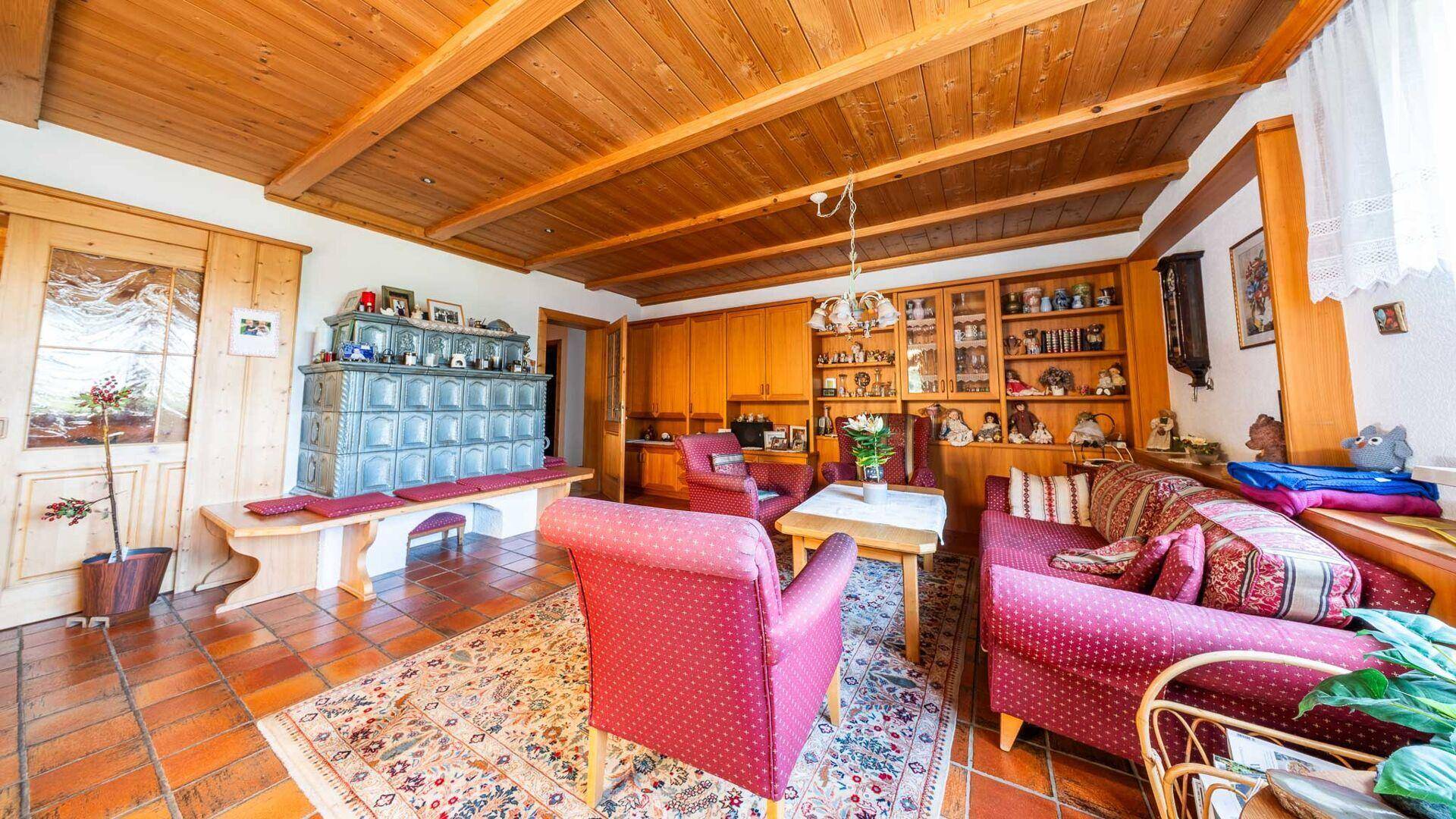 Traditionelles Wohnzimmer mit rustikalem Kachelofen, Holzmöbeln und gemütlicher Atmosphäre.