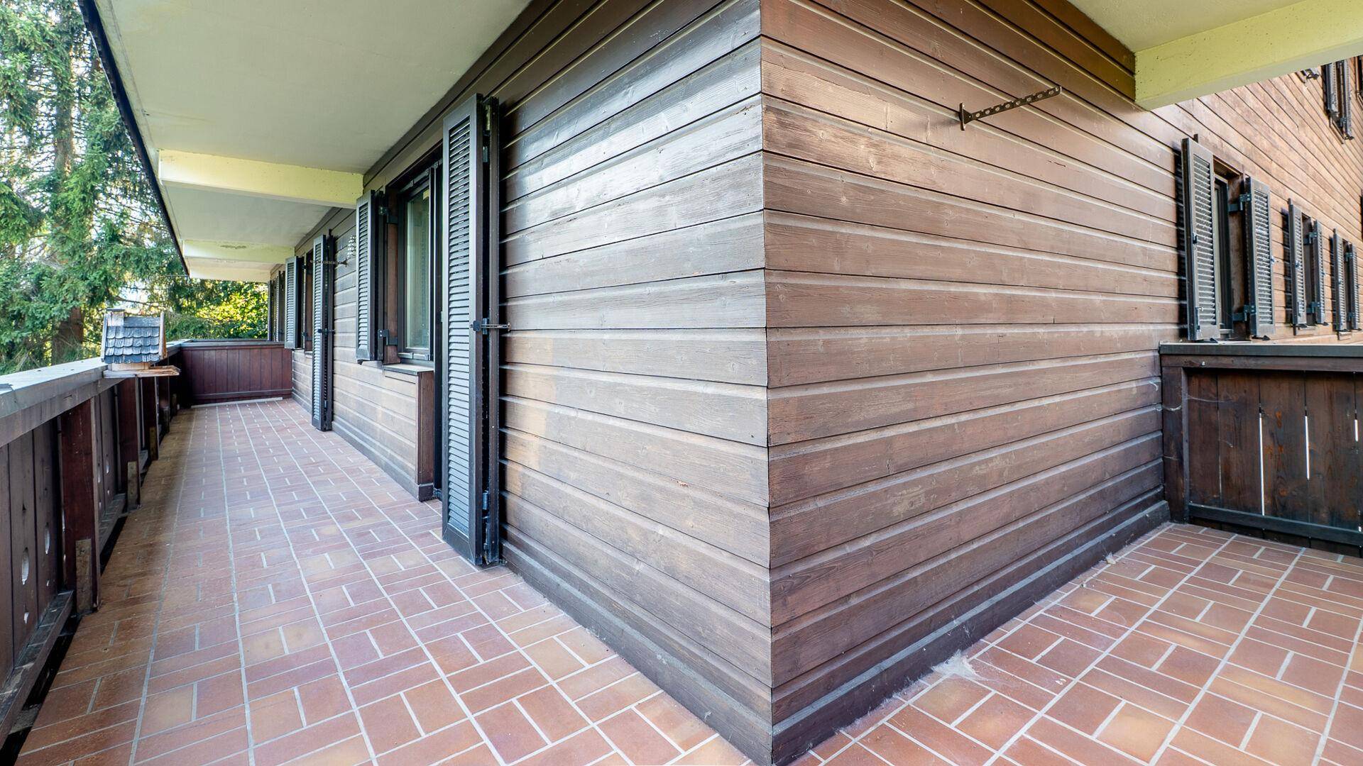 Langer Balkon mit Holzverkleidung und Terrakottafliesen, ideal für entspannte Stunden im Freien.
