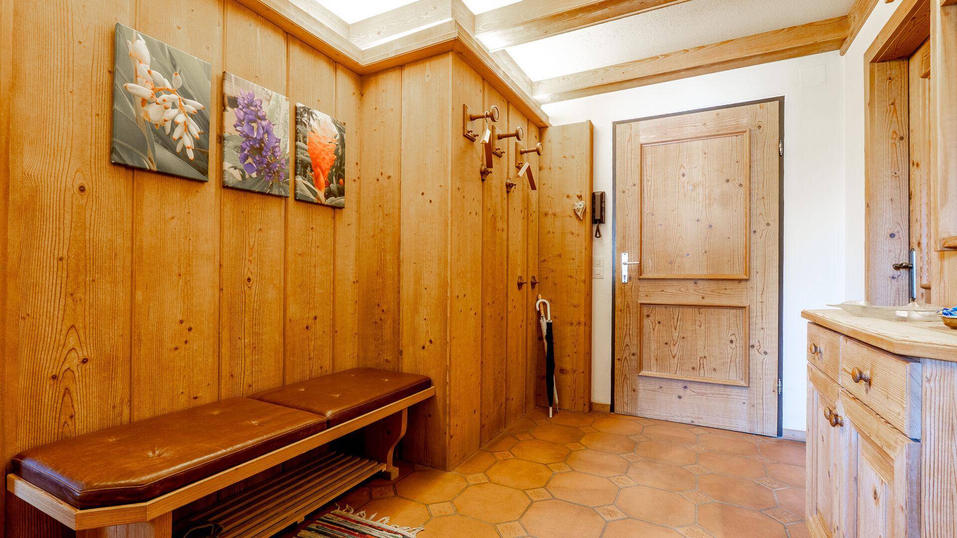 Eingangsbereich im alpinen Stil mit Holzvertäfelung, Garderobe und Sitzbank.