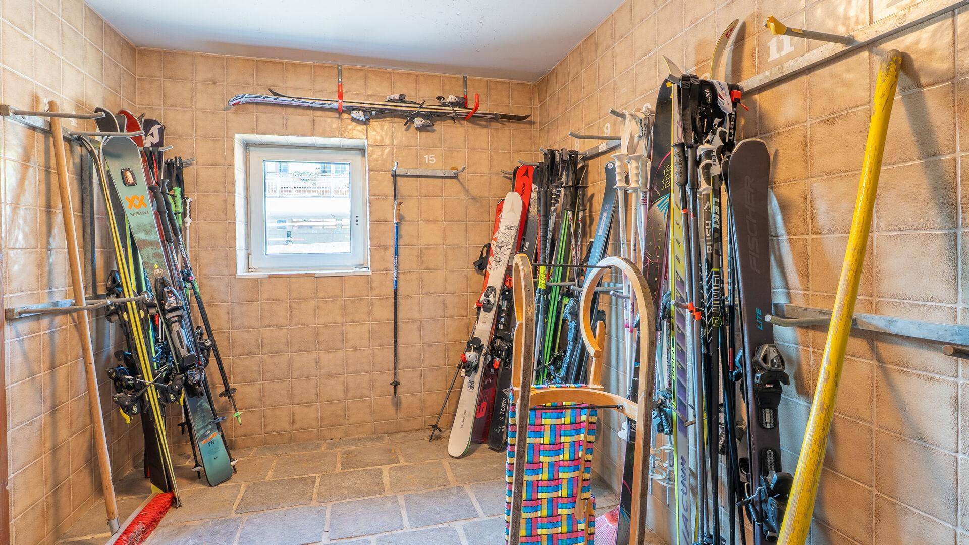 Praktischer Skiraum mit Halterungen für Skier, Snowboards und Schlitten.