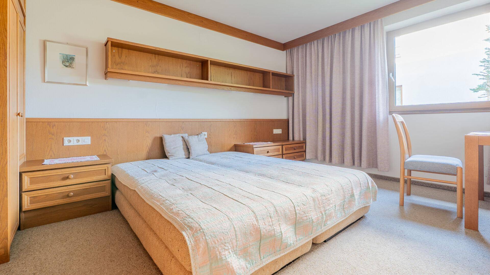 Gemütliches Schlafzimmer mit zwei Einzelbetten, Teppichboden und Holzmöbeln im traditionellen Stil.
