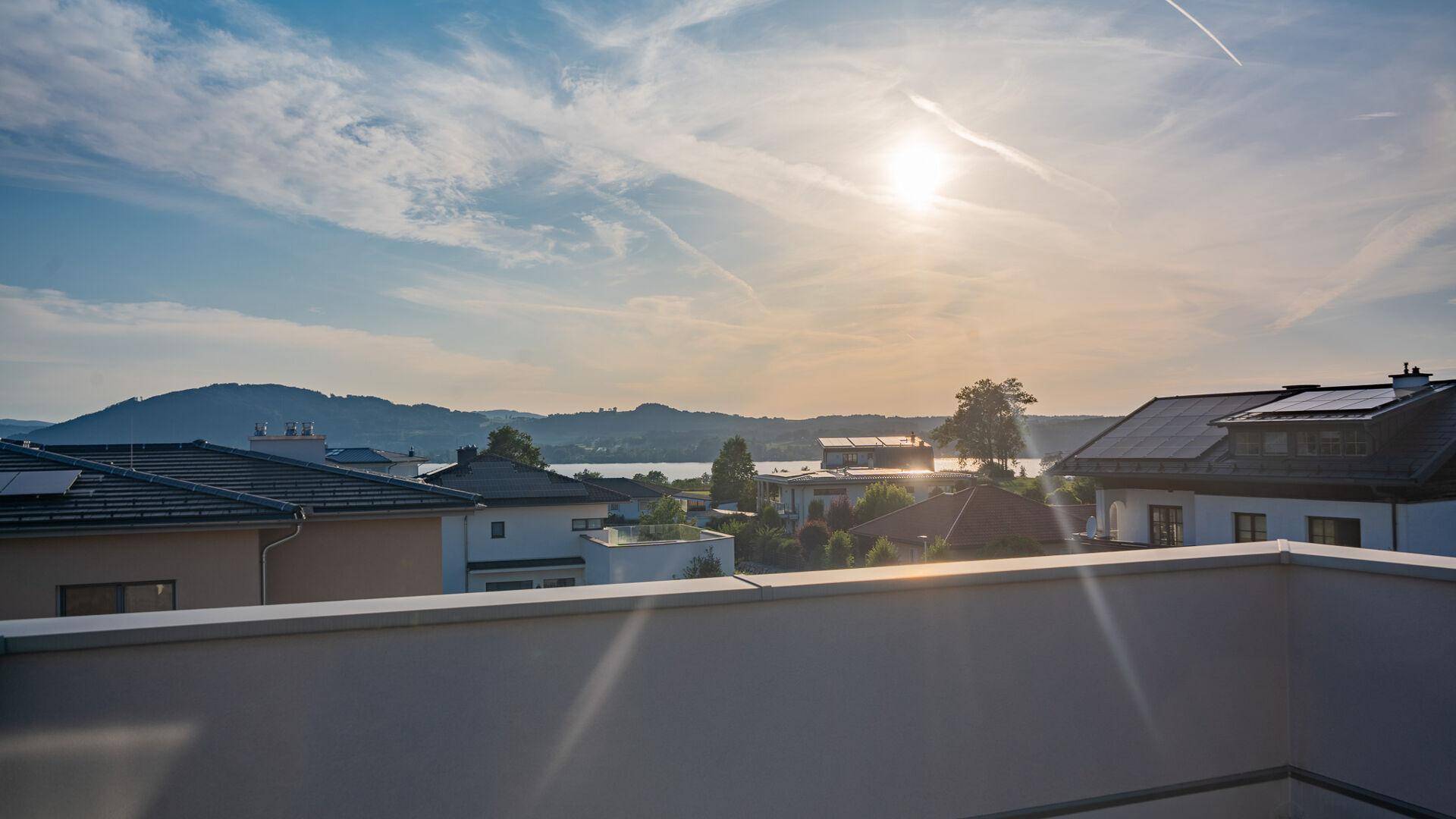 Unmöblierte Terrasse mit weitem Blick auf den See, die bewaldeten Hügel und die umliegende Bebauung.