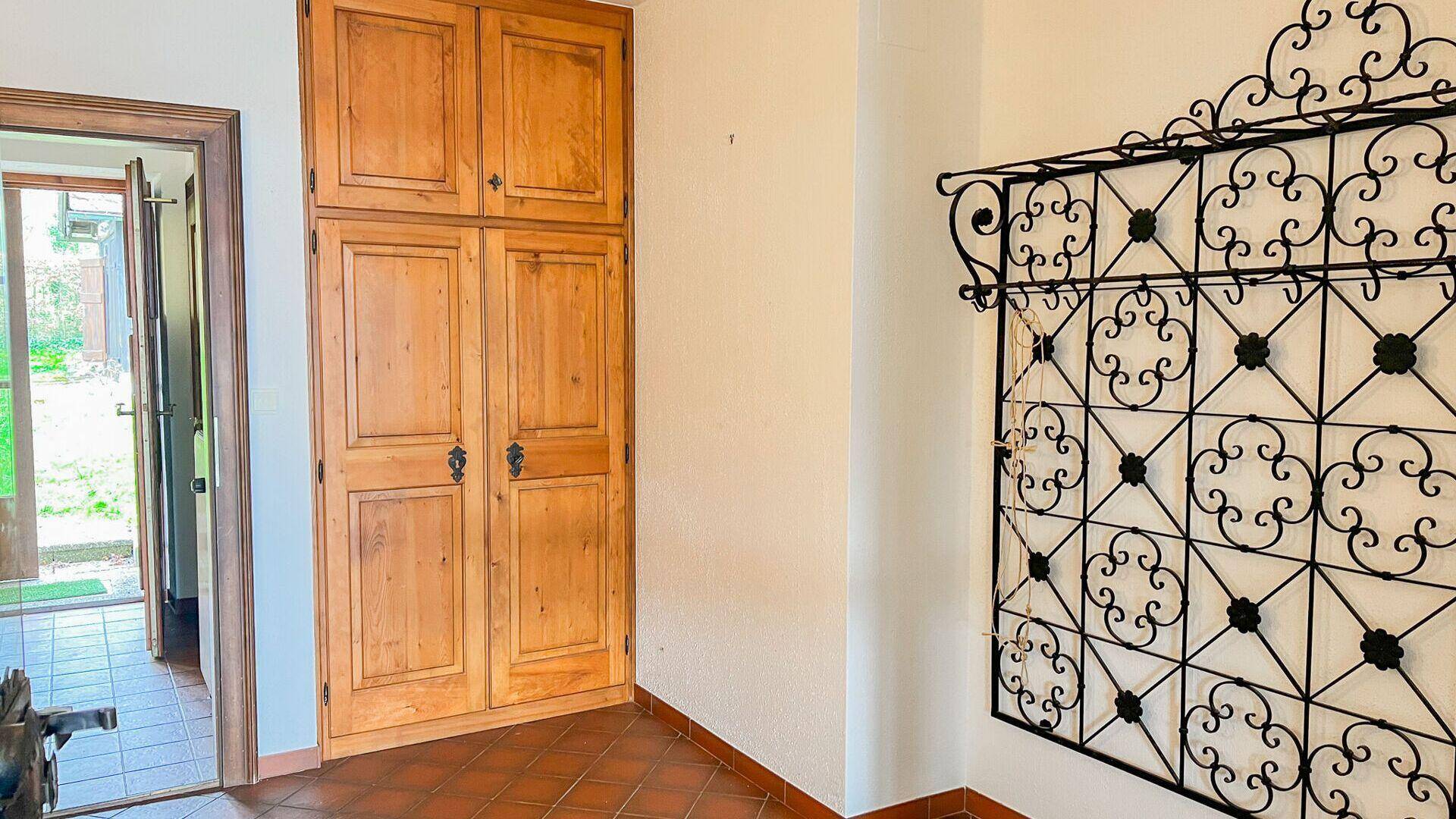 Eingangsbereich mit Terrakottafliesen, Einbauschrank aus Holz und dekorativer Wandverzierung.