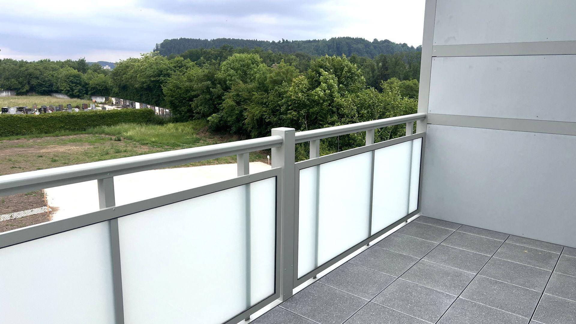 Balkon mit grauen Fliesen und einer klaren Aussicht ins Grüne, ideal zum Entspannen im Freien.
