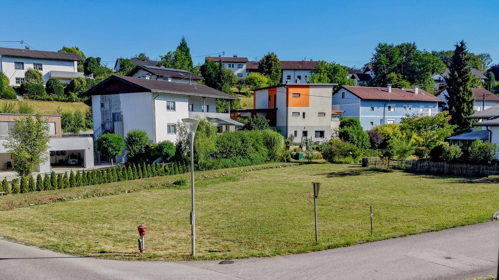 Panoramablick auf eine Wohnsiedlung mit verschiedenen Häusern und weitläufigen Grünflächen.