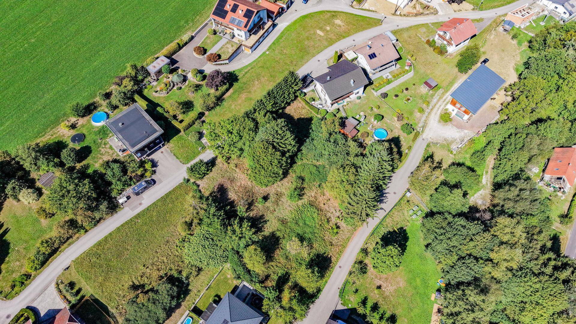 Detaillierte Luftansicht eines Grundstücks in einer ruhigen Wohnsiedlung mit angrenzenden Häusern und Wegen.