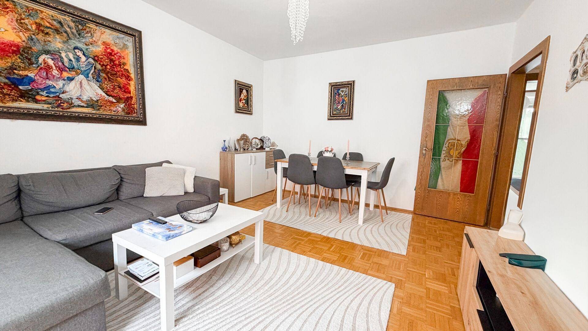 Geräumiges Wohn- und Esszimmer mit Parkettboden, bequemer Sitzecke und Esstisch für mehrere Personen.
