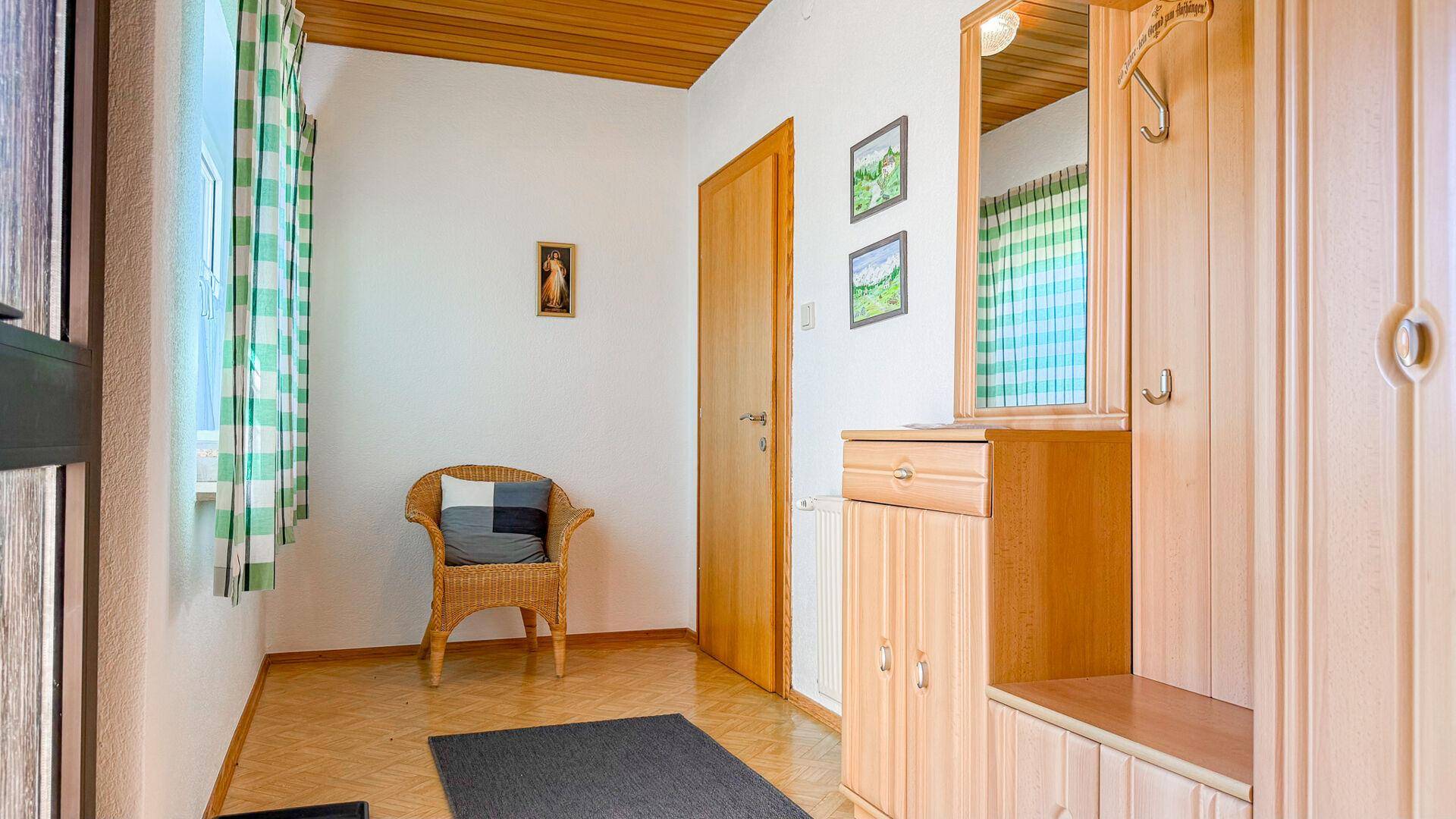 Heller Eingangsbereich mit Garderobe, Holzdecke und hellem Laminatboden.