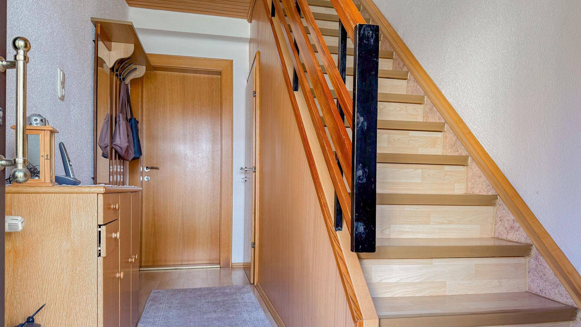 Flur mit Holztreppe, Garderobe und Zugang zu weiteren Räumen im Obergeschoss.