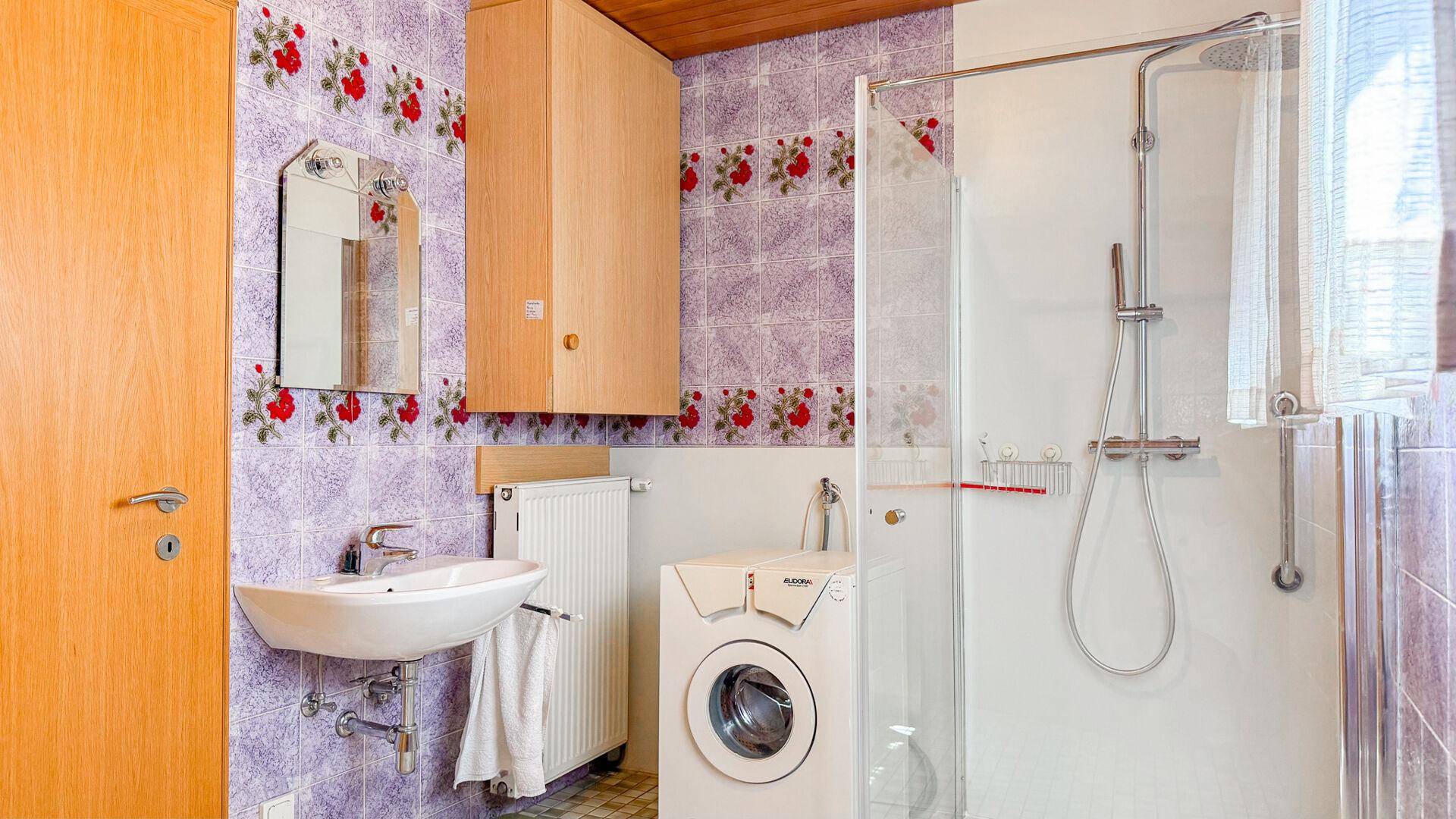 Badezimmer mit Dusche, Waschmaschine und farbenfrohen Fliesen im traditionellen Stil.