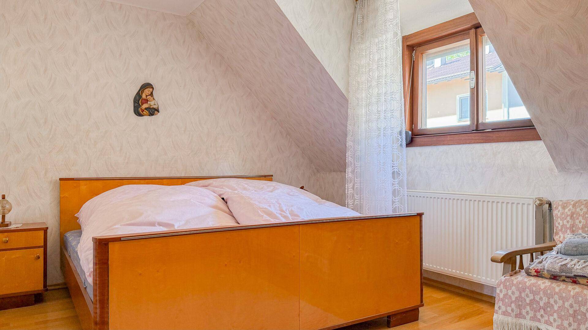 Gemütliches Schlafzimmer im Dachgeschoss mit Doppelbett und schräger Decke.