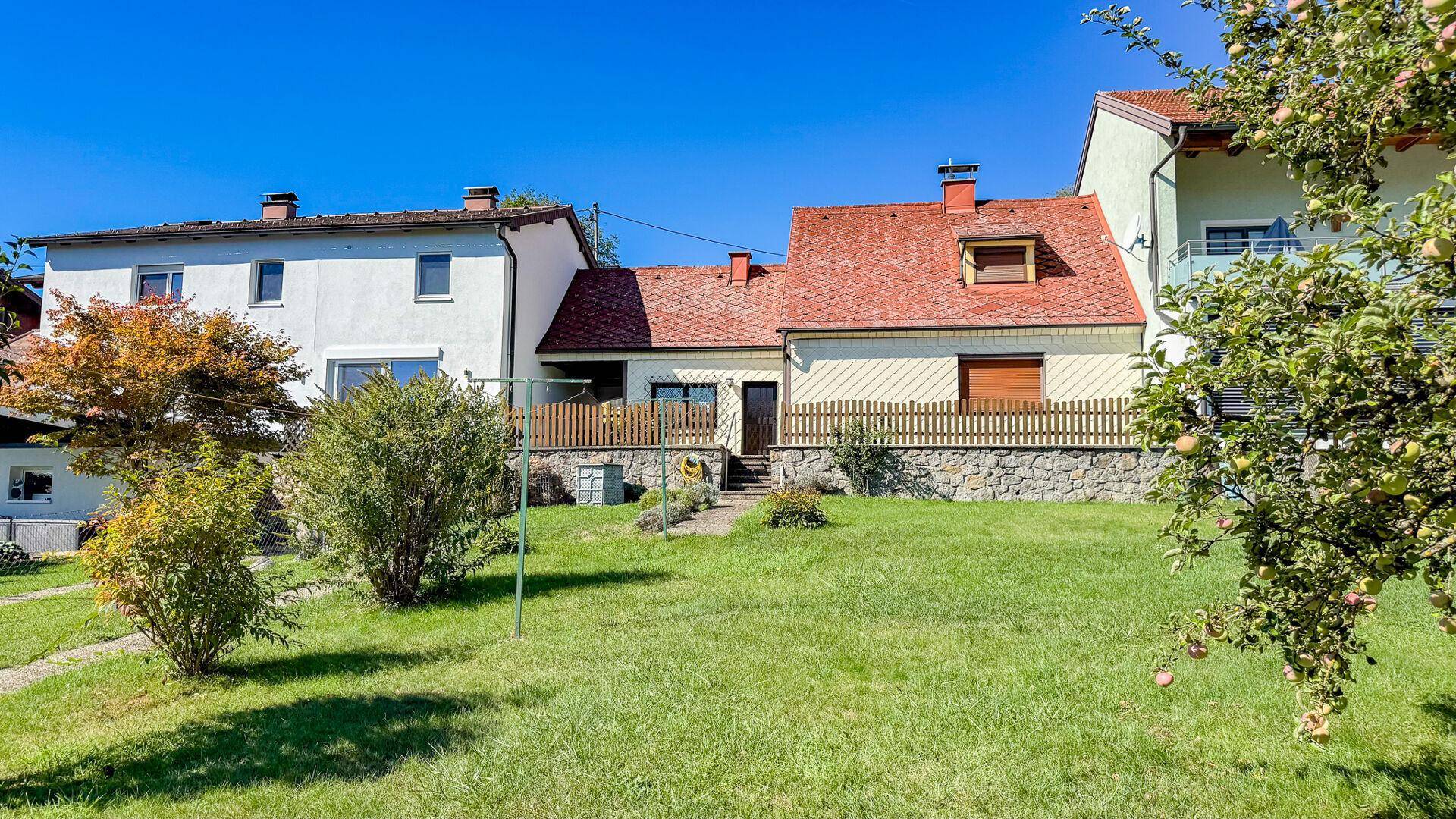 Rückansicht des Hauses mit großem Garten, Rasenfläche und angrenzenden Gebäuden.