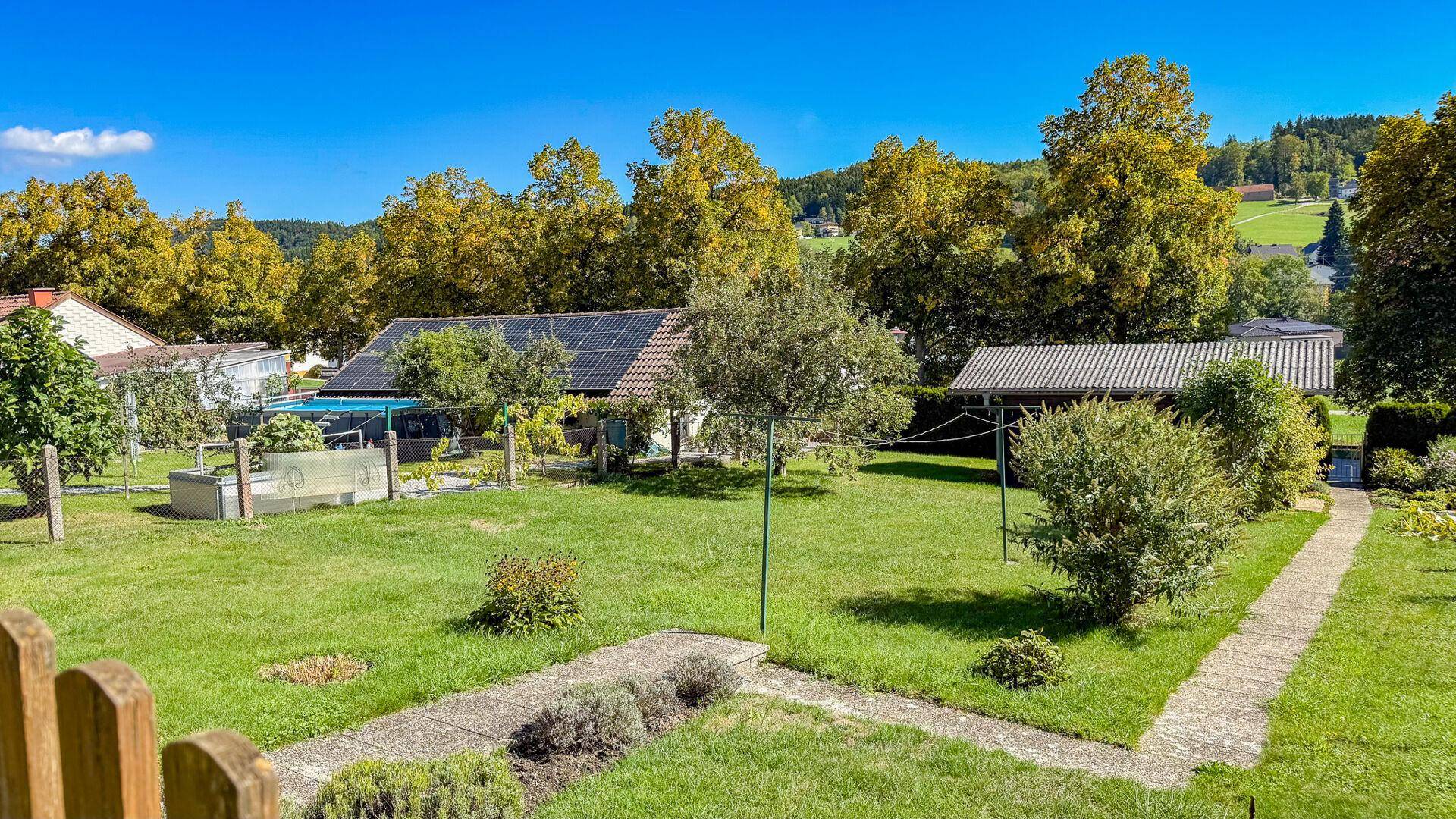 Großer, gepflegter Garten mit Rasenfläche, Bäumen und weitem Blick in die Landschaft.