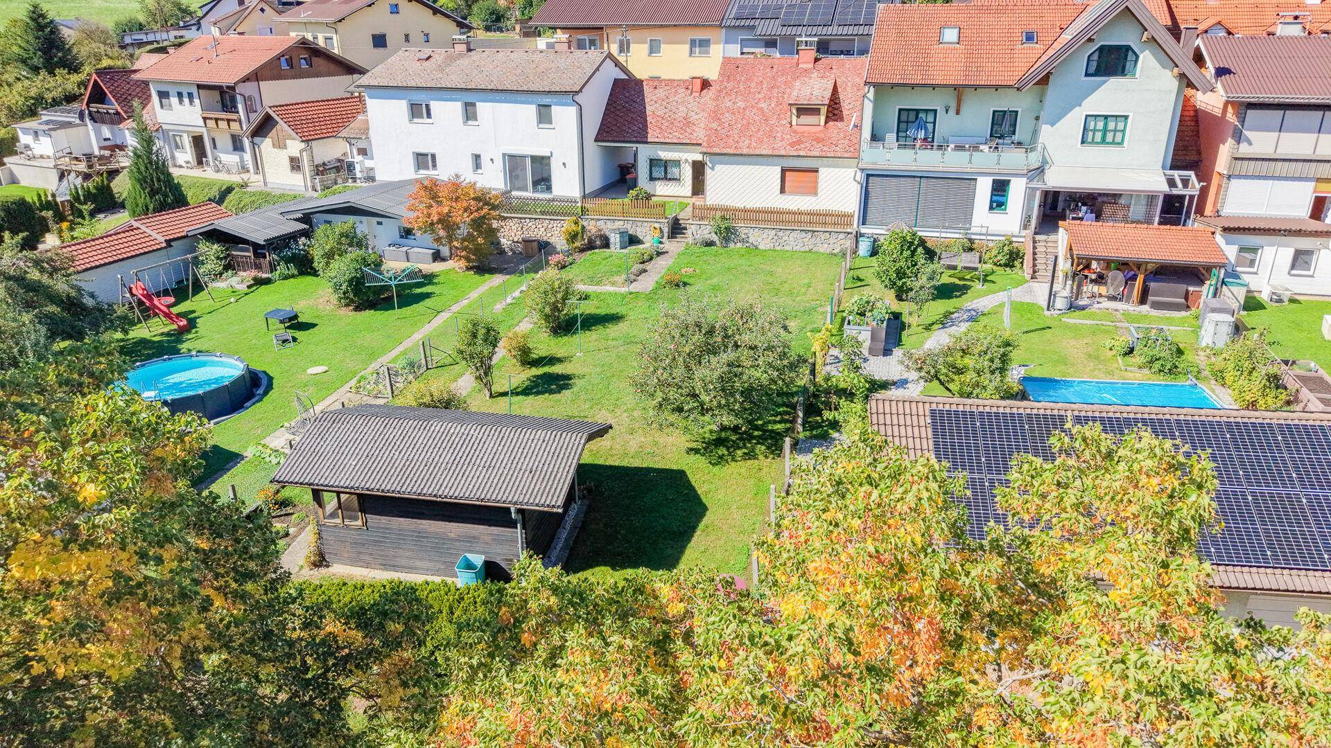 Luftaufnahme des Anwesens mit großem Garten, Pool, Spielplatz und umliegender Bebauung.