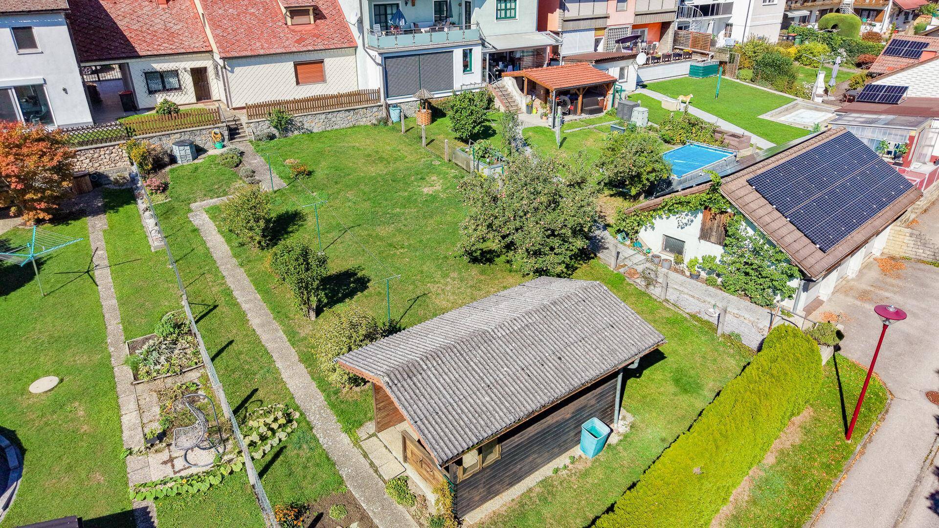 Luftaufnahme des weitläufigen Gartens mit Schuppen, Pool und Nachbarhäusern.