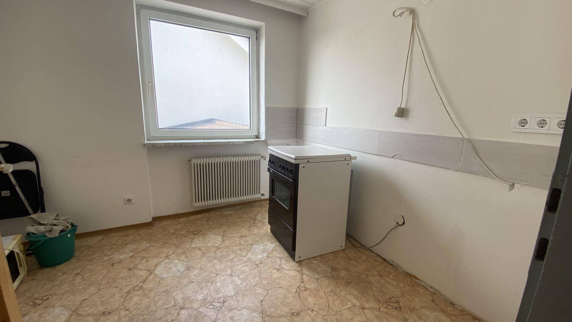 Leere Küche mit einem freistehenden Herd und einem Fenster, bereit zur individuellen Gestaltung.