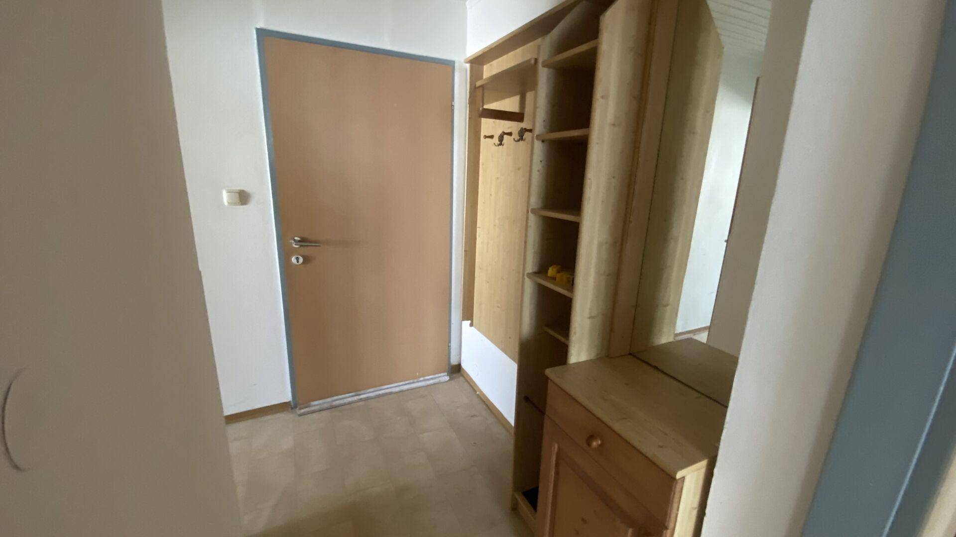 Eingangsbereich mit Holztür und praktischem Einbauschrank für Garderobe und Stauraum.