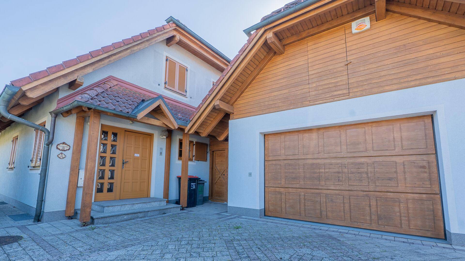 Eingangsbereich des Hauses mit Holzverkleidung und angrenzender Garage in traditionellem Stil.