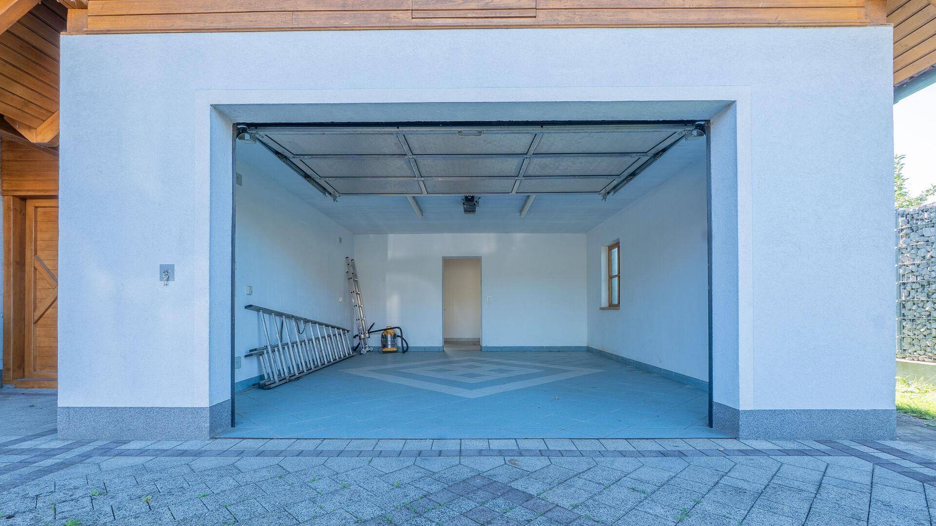 Geräumige, leere Garage mit offenem Tor und ausreichend Platz für Fahrzeuge oder Lagerung.
