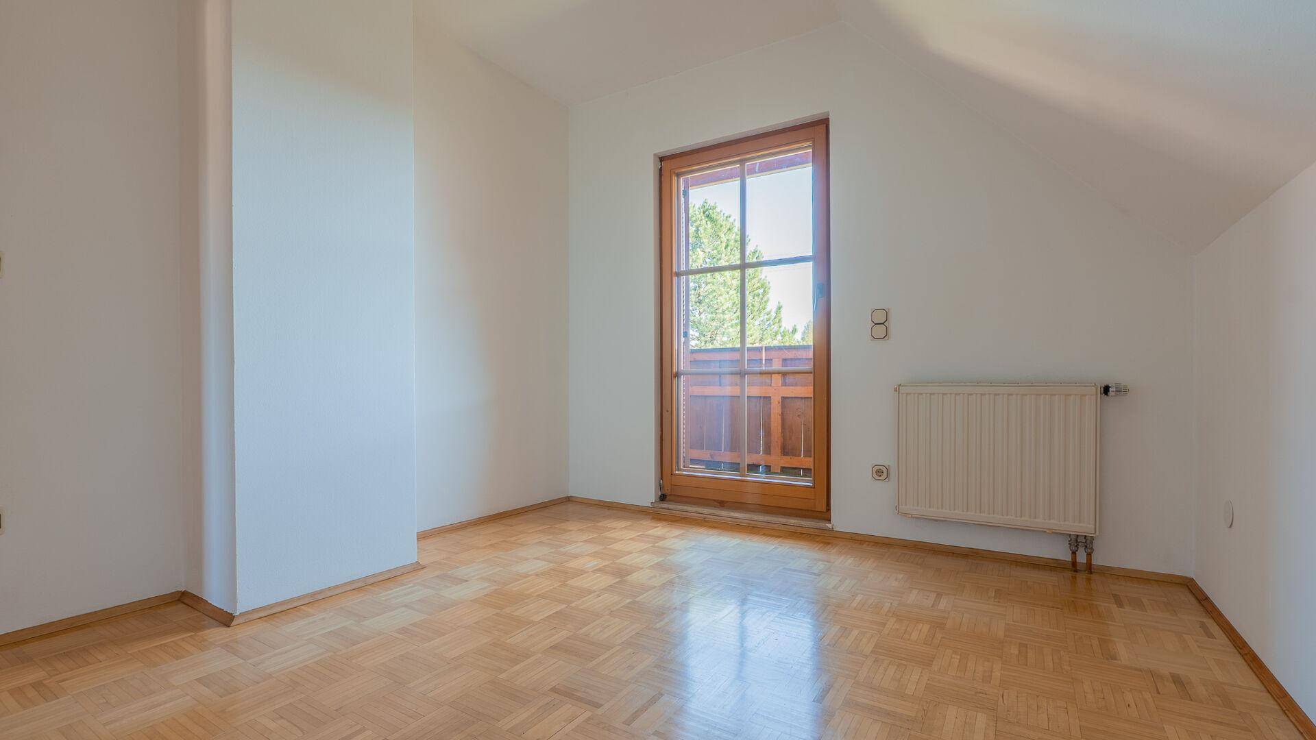 Helles Schlafzimmer mit Parkettboden, Dachschräge und direktem Zugang zum Balkon.