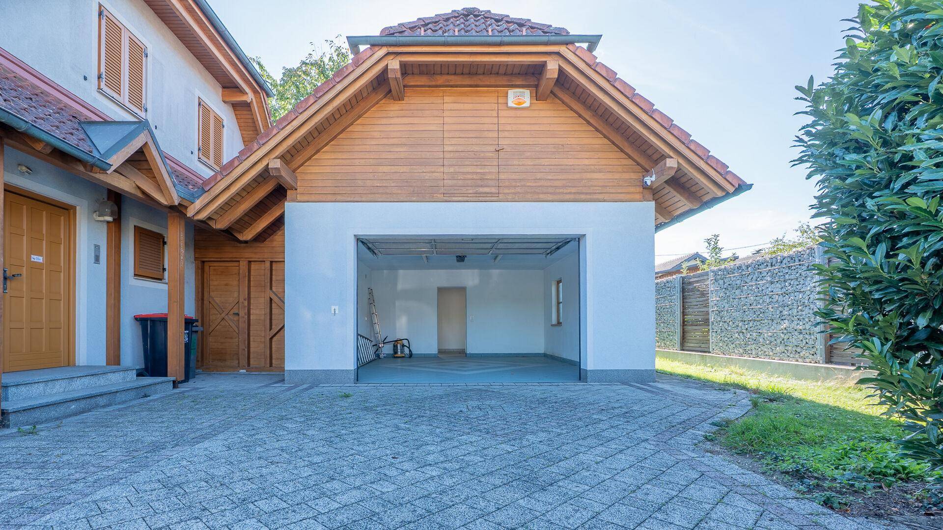 Offene Garage mit Blick auf den Innenraum und die gepflasterte Zufahrt.