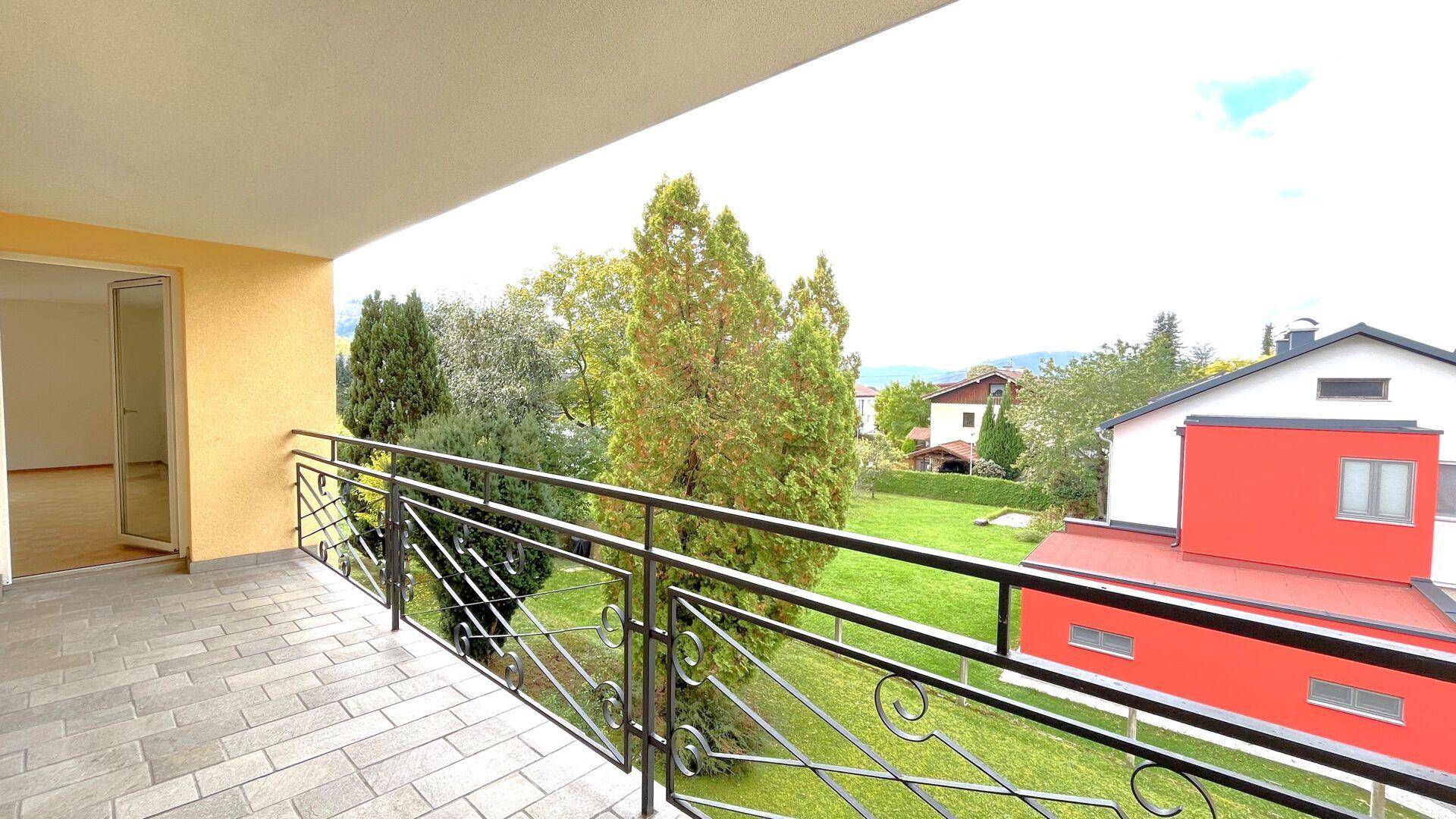 Geräumiger Balkon mit Fliesenboden und schmiedeeisernem Geländer, bietet Blick ins Grüne und auf die Umgebung.