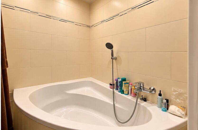 Modernes Badezimmer mit Eckbadewanne und beigefarbenen Fliesen, gut beleuchtet.