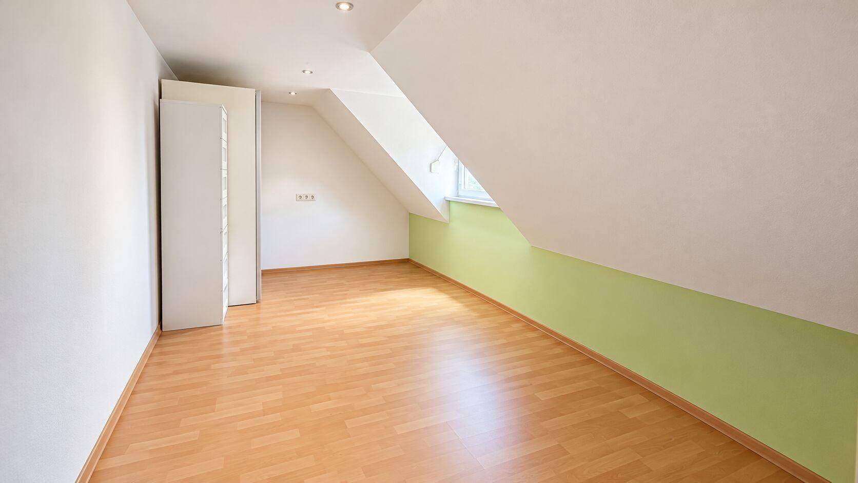 Helles Dachzimmer mit Laminatboden und schrägen Wänden, vielseitig nutzbar.
