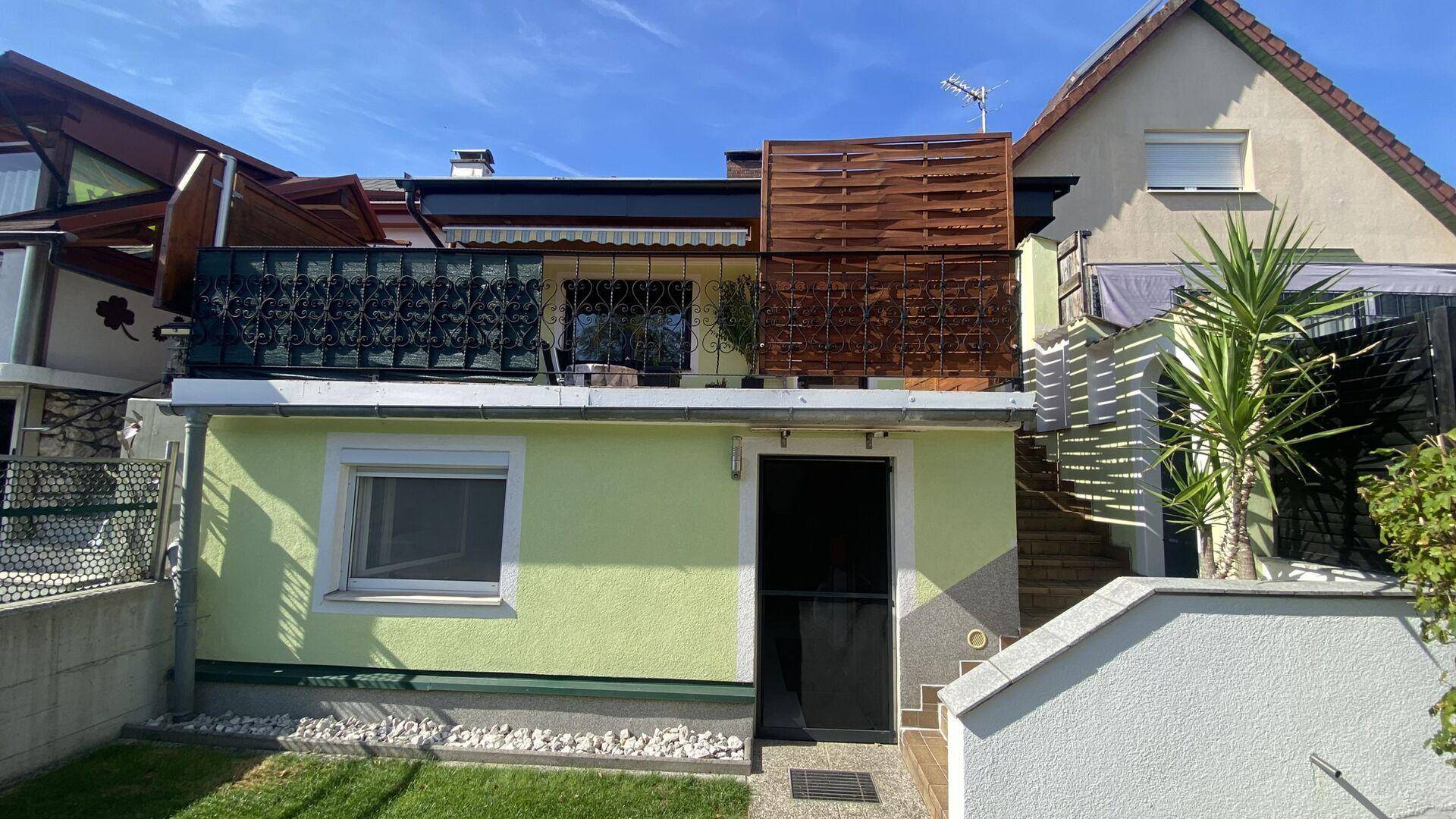 Rückansicht des Hauses mit kleinem Gartenbereich und Balkon im Obergeschoss.