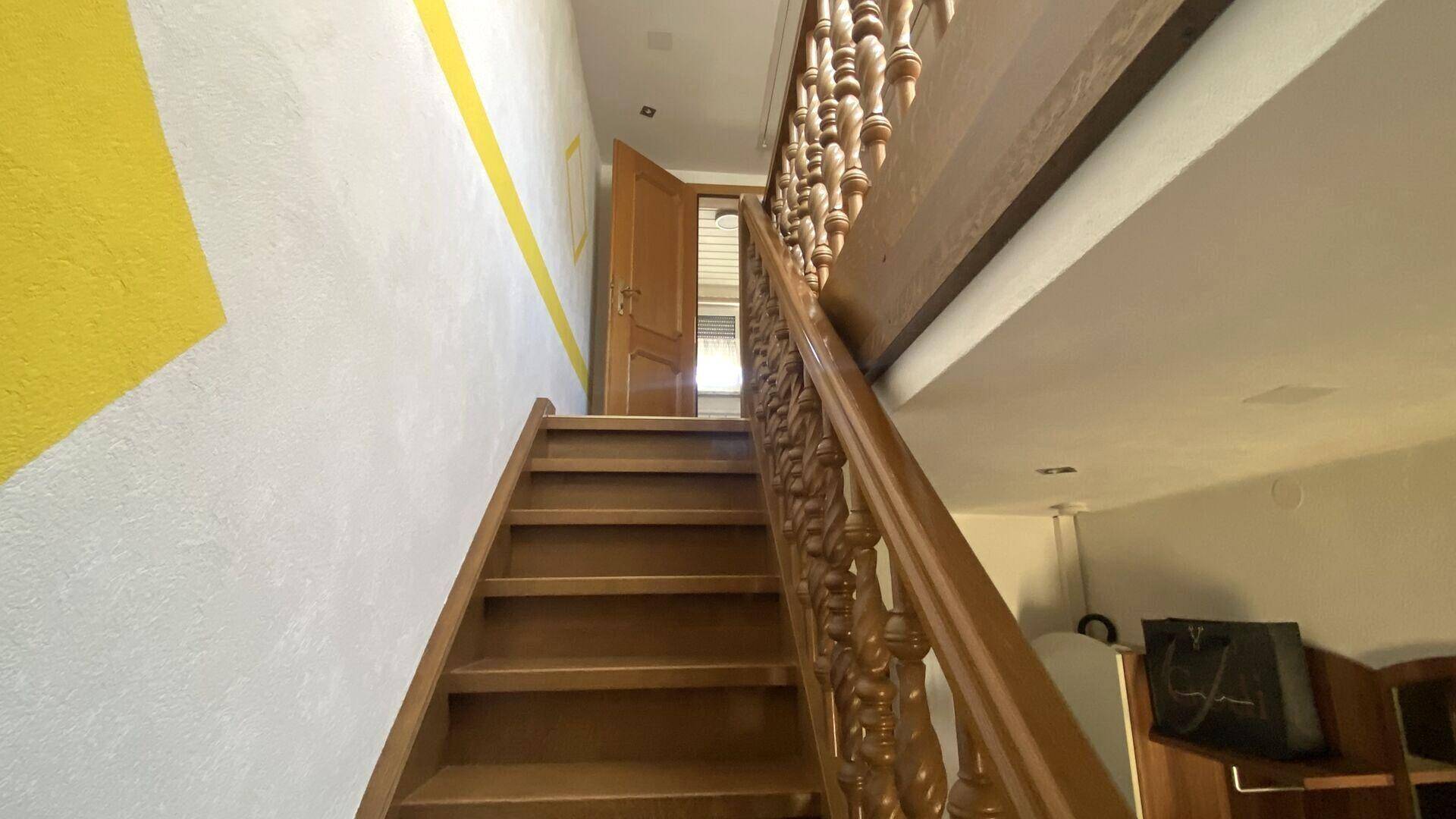 Holztreppe mit gedrechseltem Geländer führt in die oberen Etagen des Hauses.