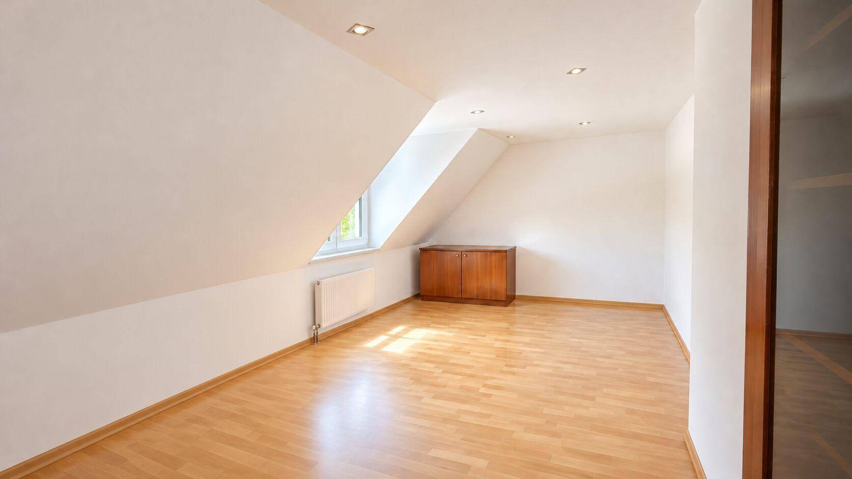 Geräumiges Dachzimmer mit Laminatboden, Dachfenster und Einbauschrank.