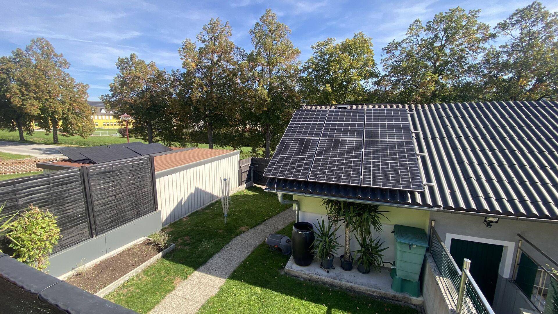 Übersicht über den Gartenbereich mit Photovoltaikanlage auf dem Dach des Hauses.
