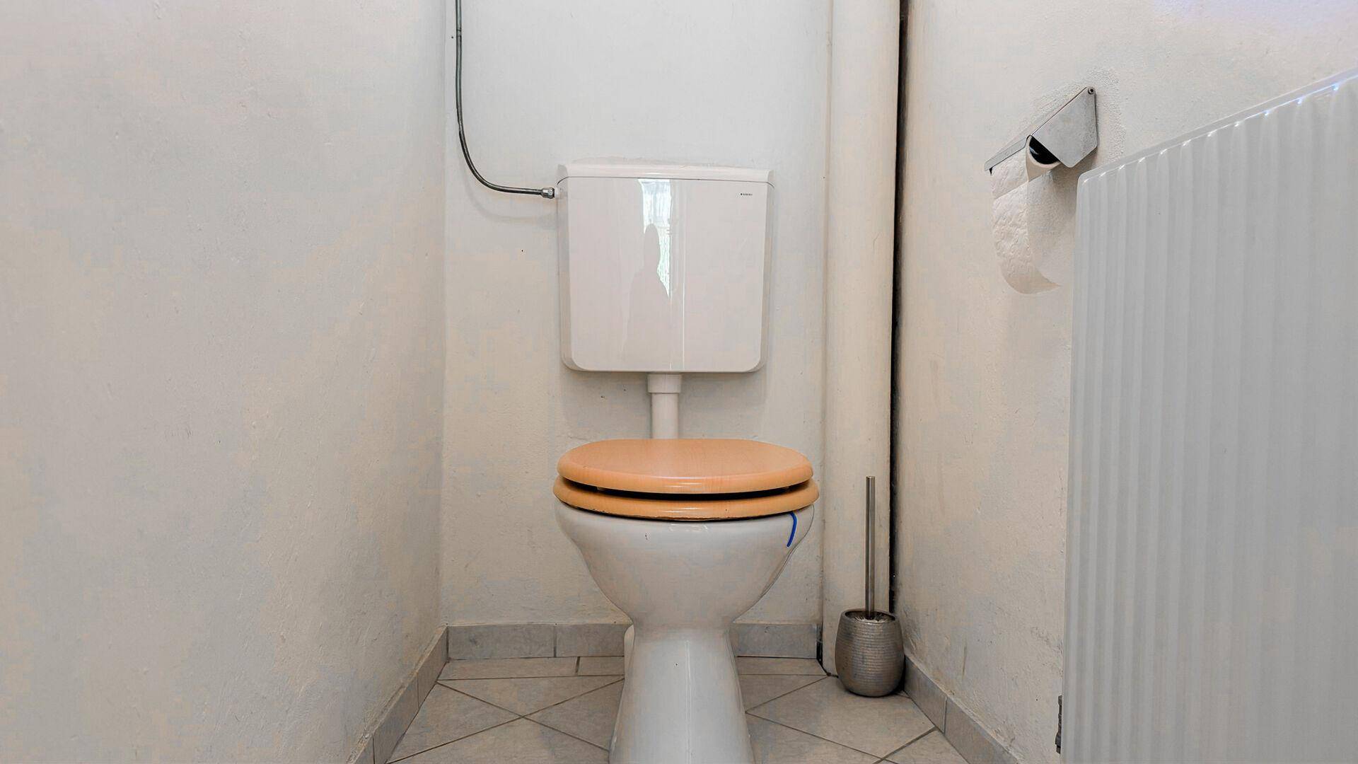 Kleines separates WC mit gefliestem Boden und Wänden, ausgestattet mit einem Heizkörper.